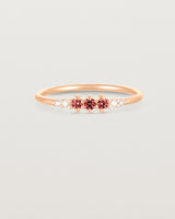 Front facing deep etched image of a rose gold ring with ruby birthstones and diamonds.