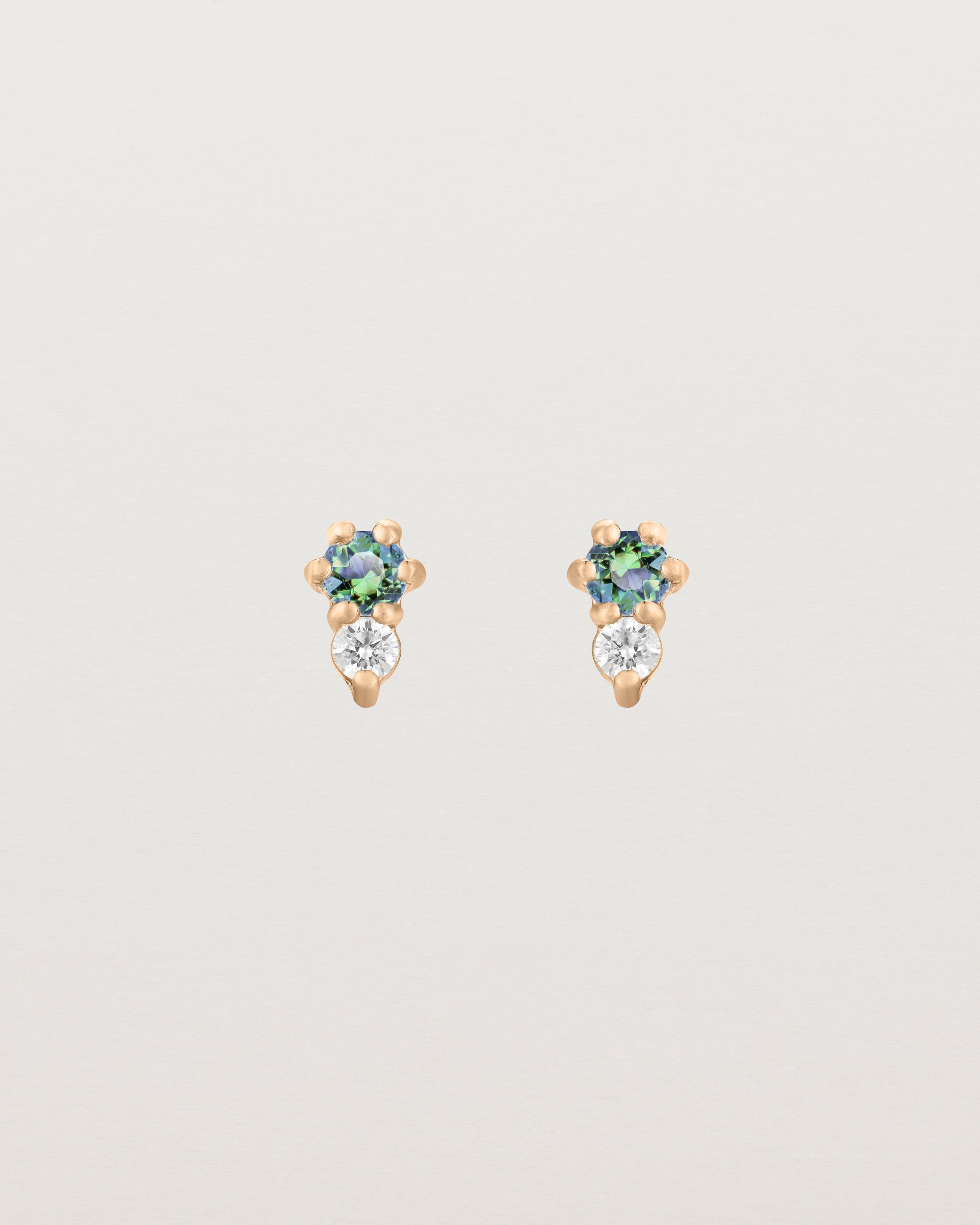 Front facing deep etched image of a pair of rose gold earrings with alexandrite birthstones and diamonds.