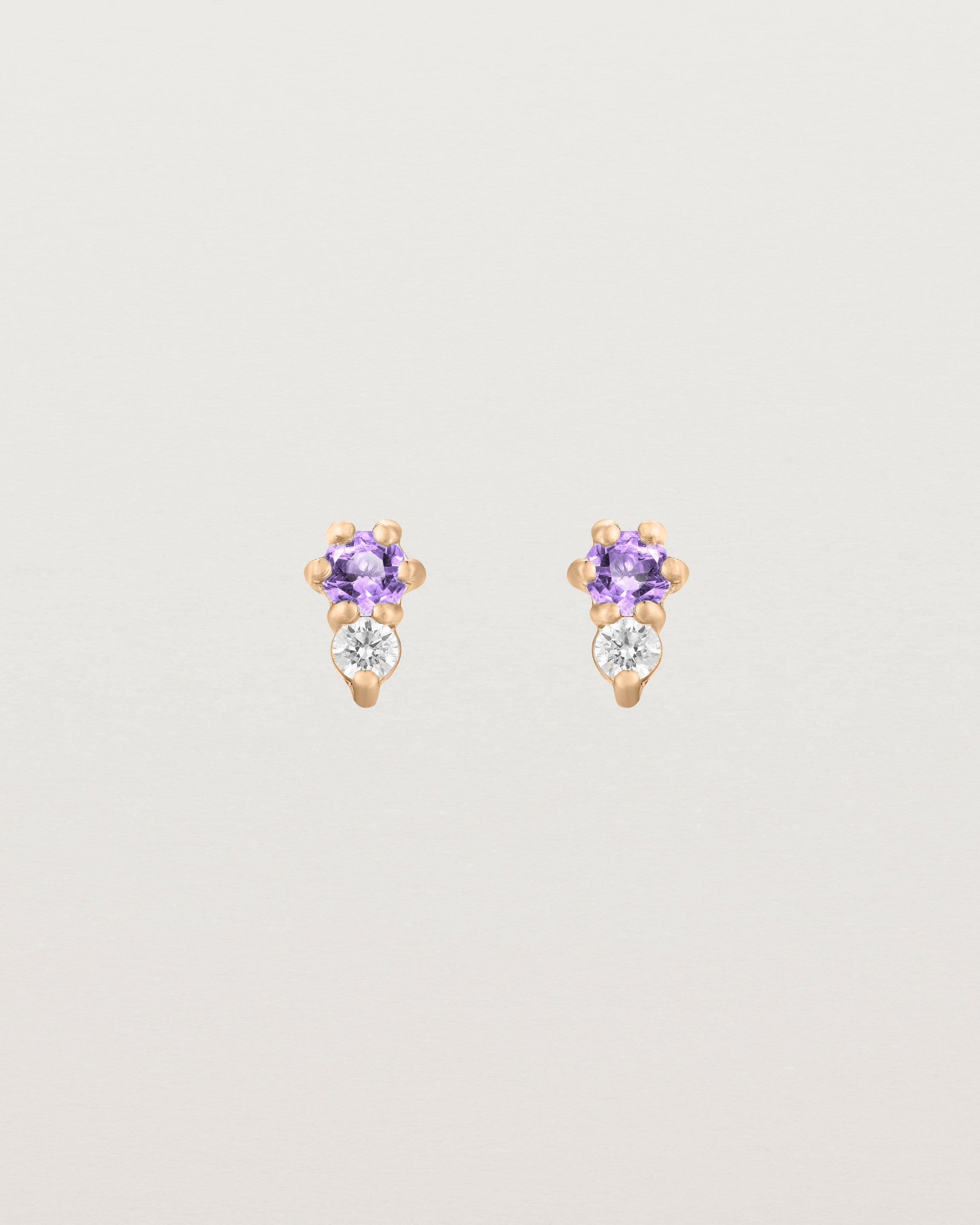 Front facing deep etched image of a pair of rose gold earrings with amethyst birthstones and diamonds.