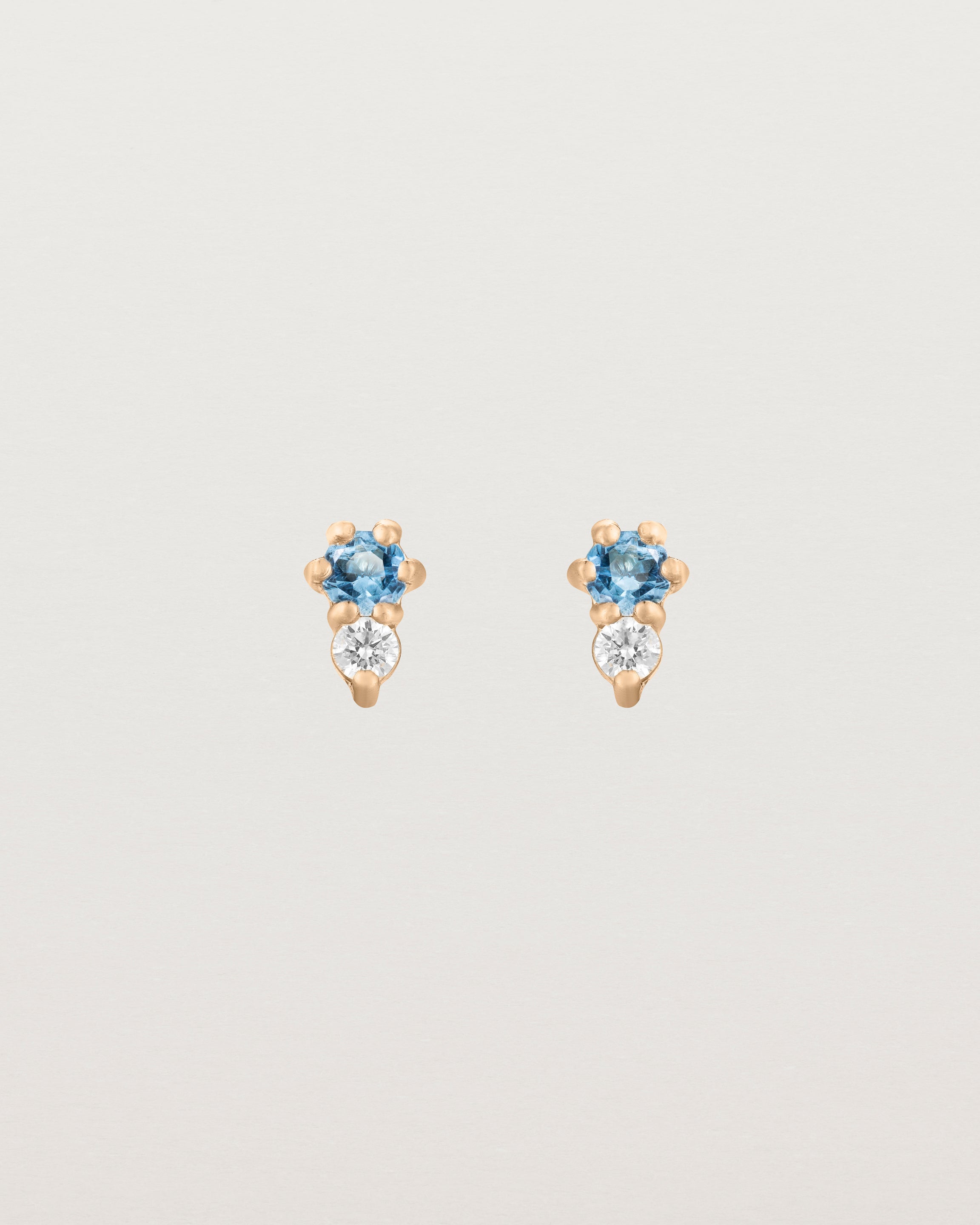 Front facing deep etched image of a pair of rose gold earrings with aquamarine birthstones and diamonds.
