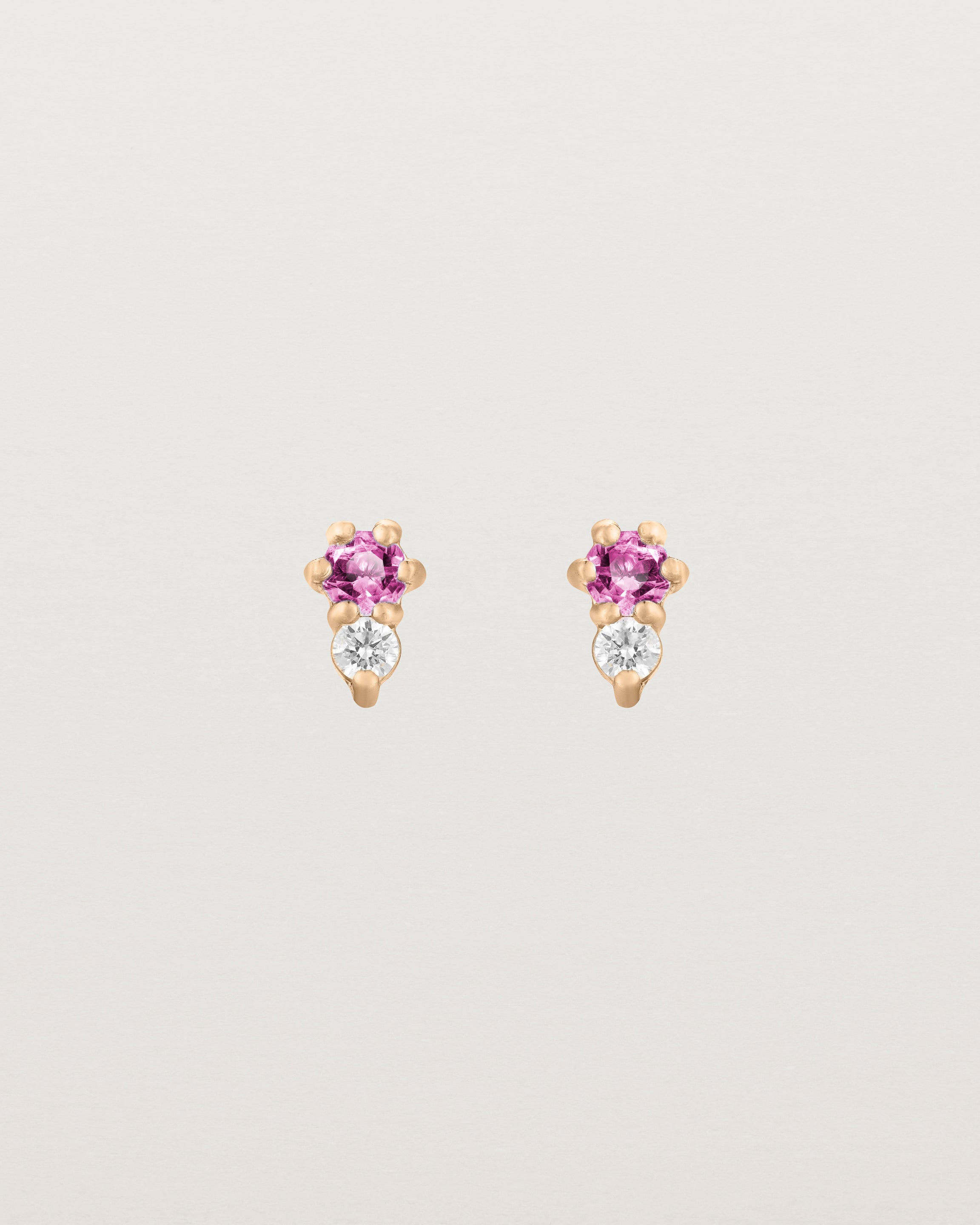 Front facing deep etched image of a pair of rose gold earrings with pink tourmaline birthstones and diamonds.