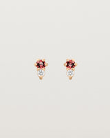 Front facing deep etched image of a pair of rose gold earrings with ruby birthstones and diamonds.