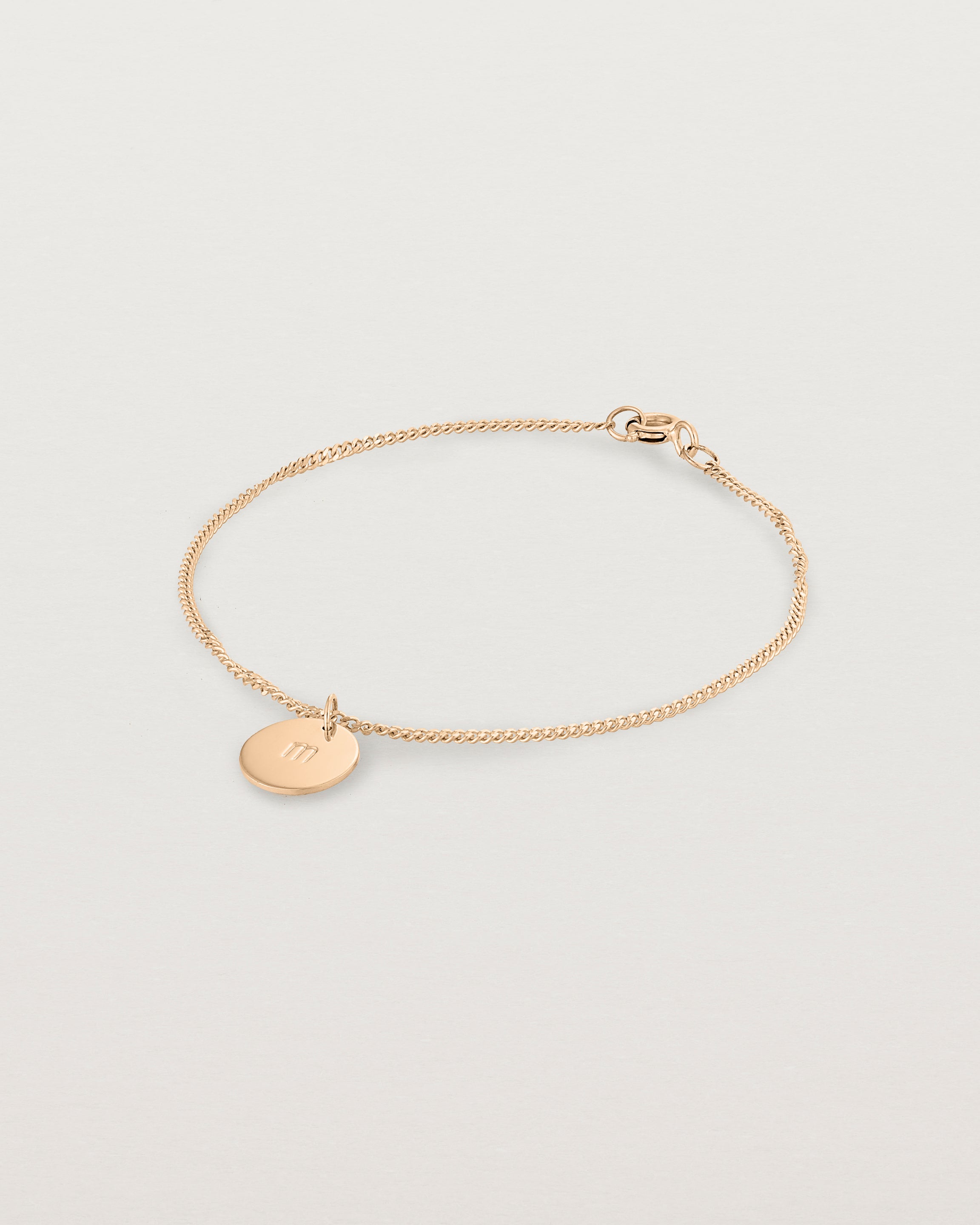 A rose rose chain bracelet featuring a disc with an engraved letter m