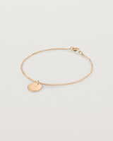 A rose rose chain bracelet featuring a disc with an engraved letter m