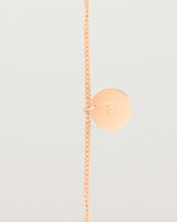 A rose gold chain bracelet featuring a disc with an engraved letter m