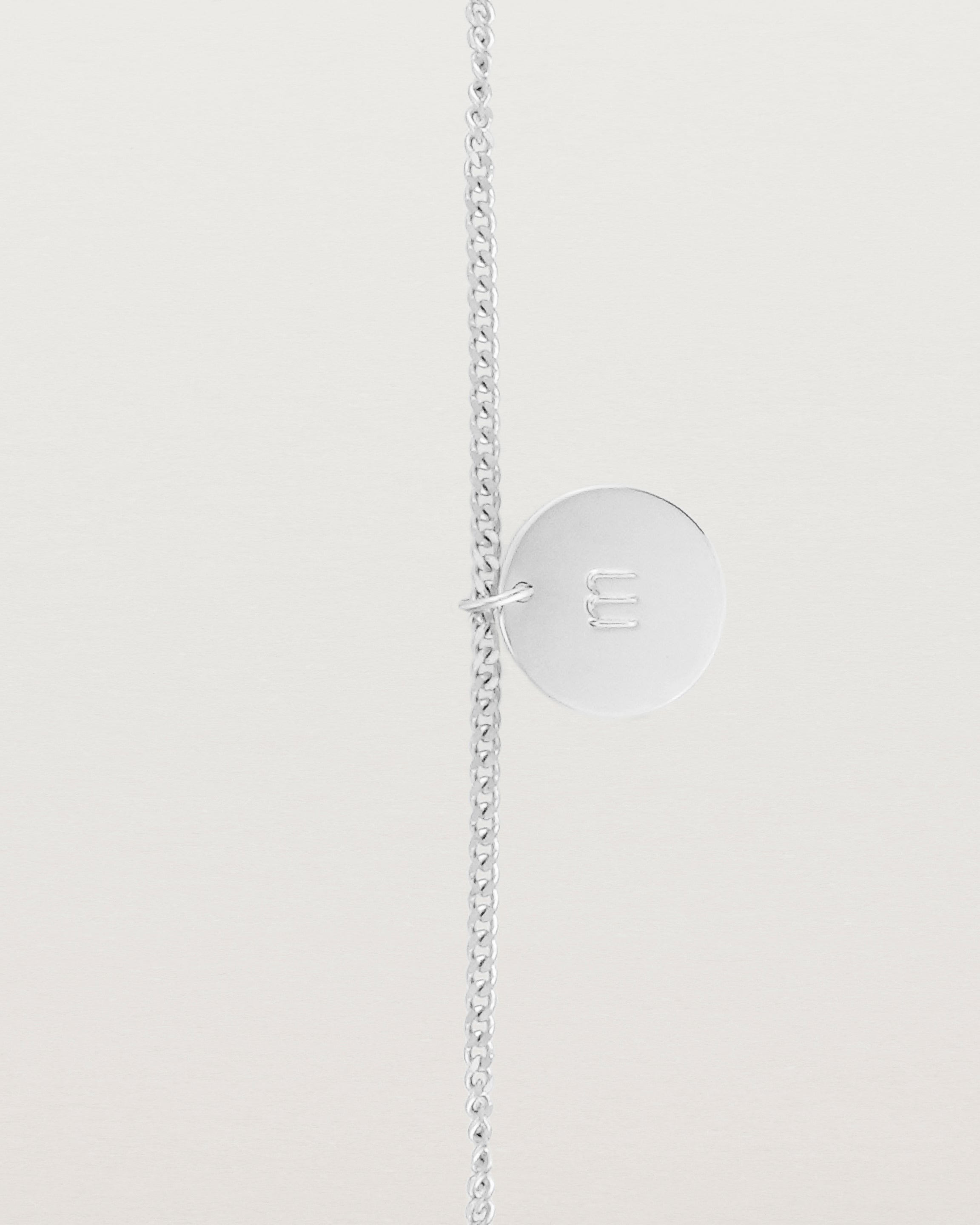 A sterling silver chain bracelet featuring a disc with an engraved letter m