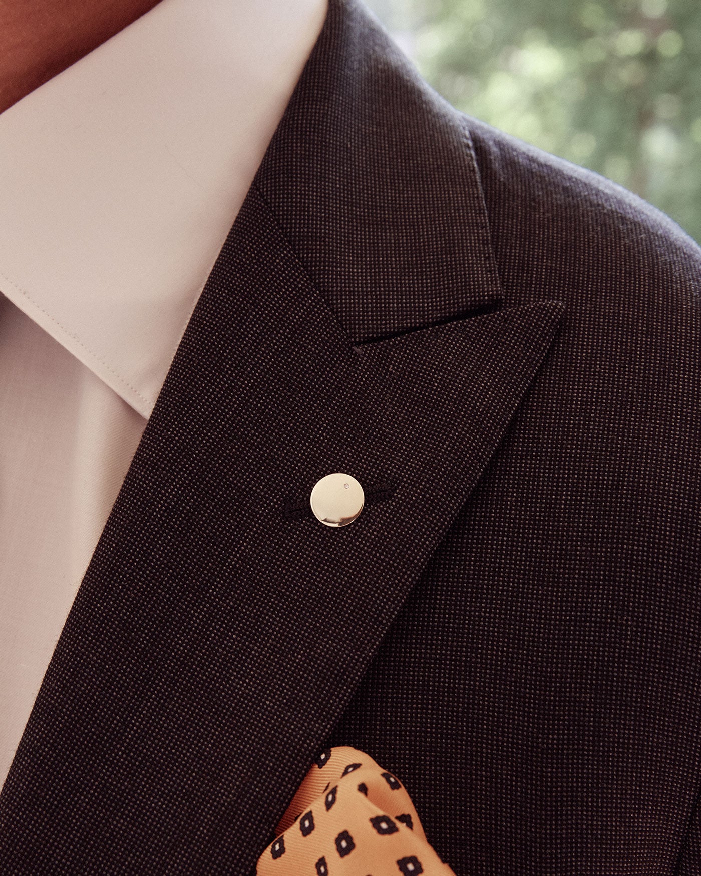 Man wearing polished gold lapel pin with white diamond