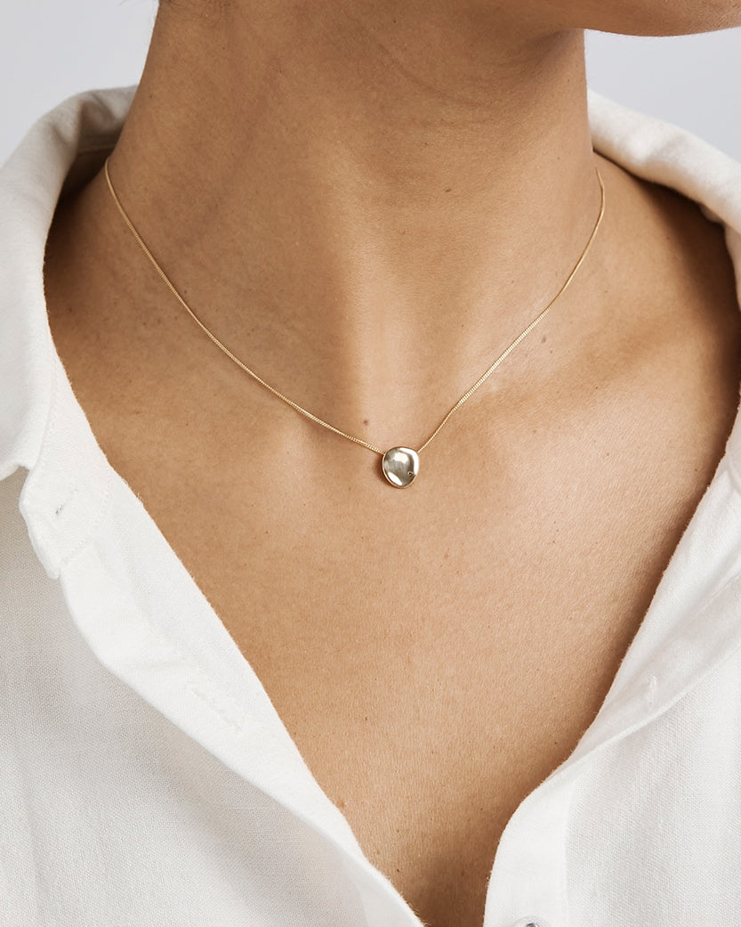 A woman wearing the Petite Mana Necklace in yellow gold.