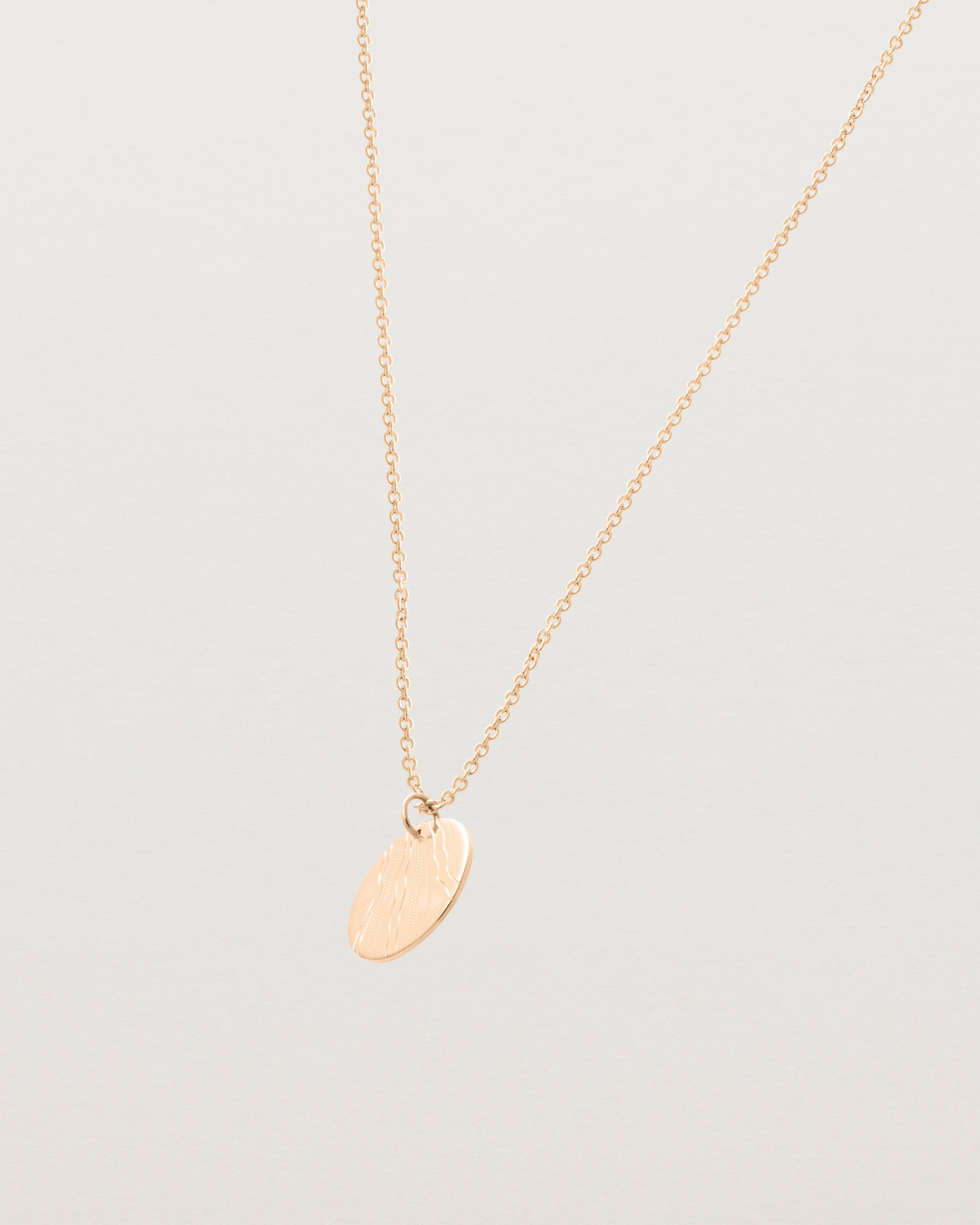 An engraved rose gold pendant
