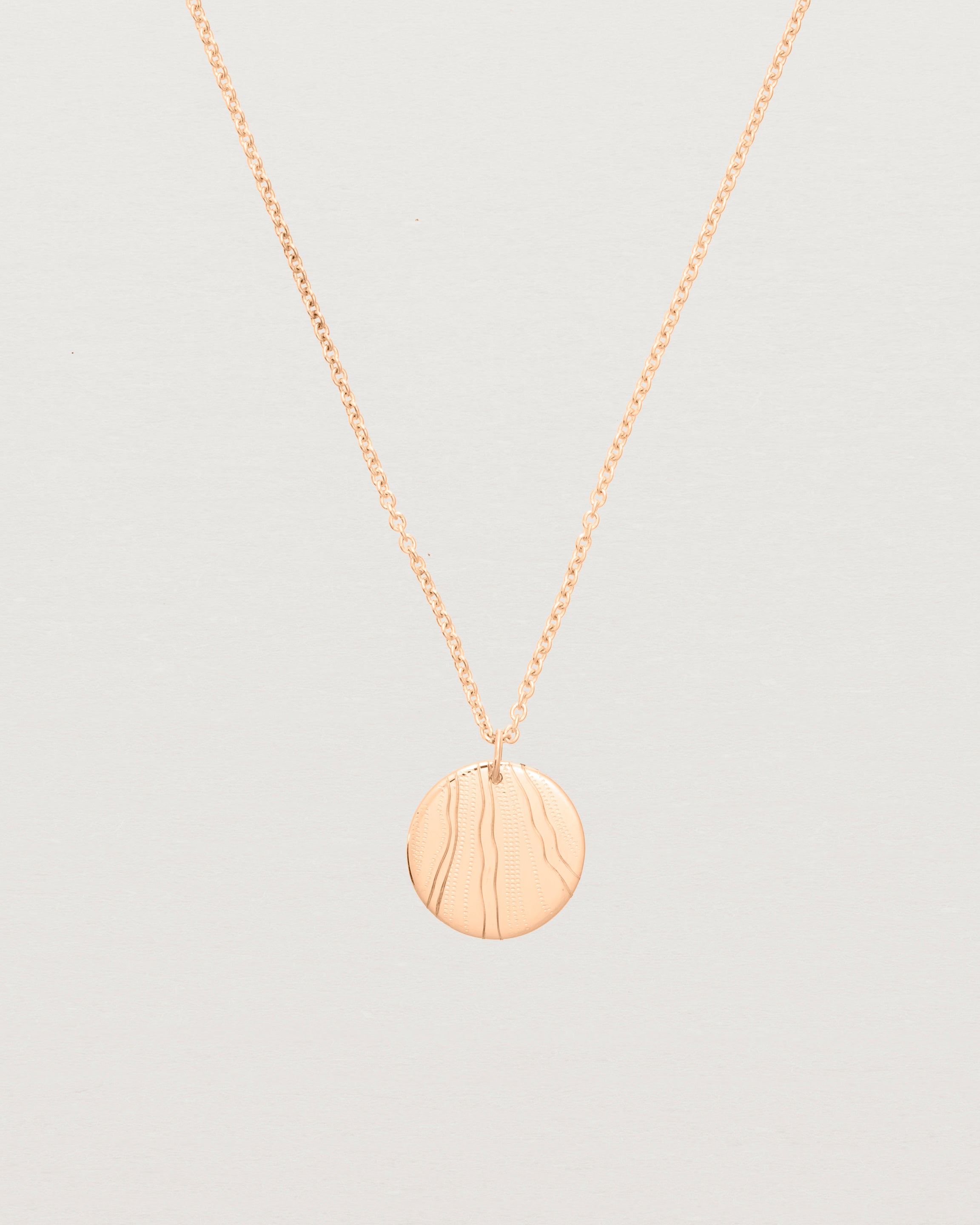 An engraved rose gold pendant