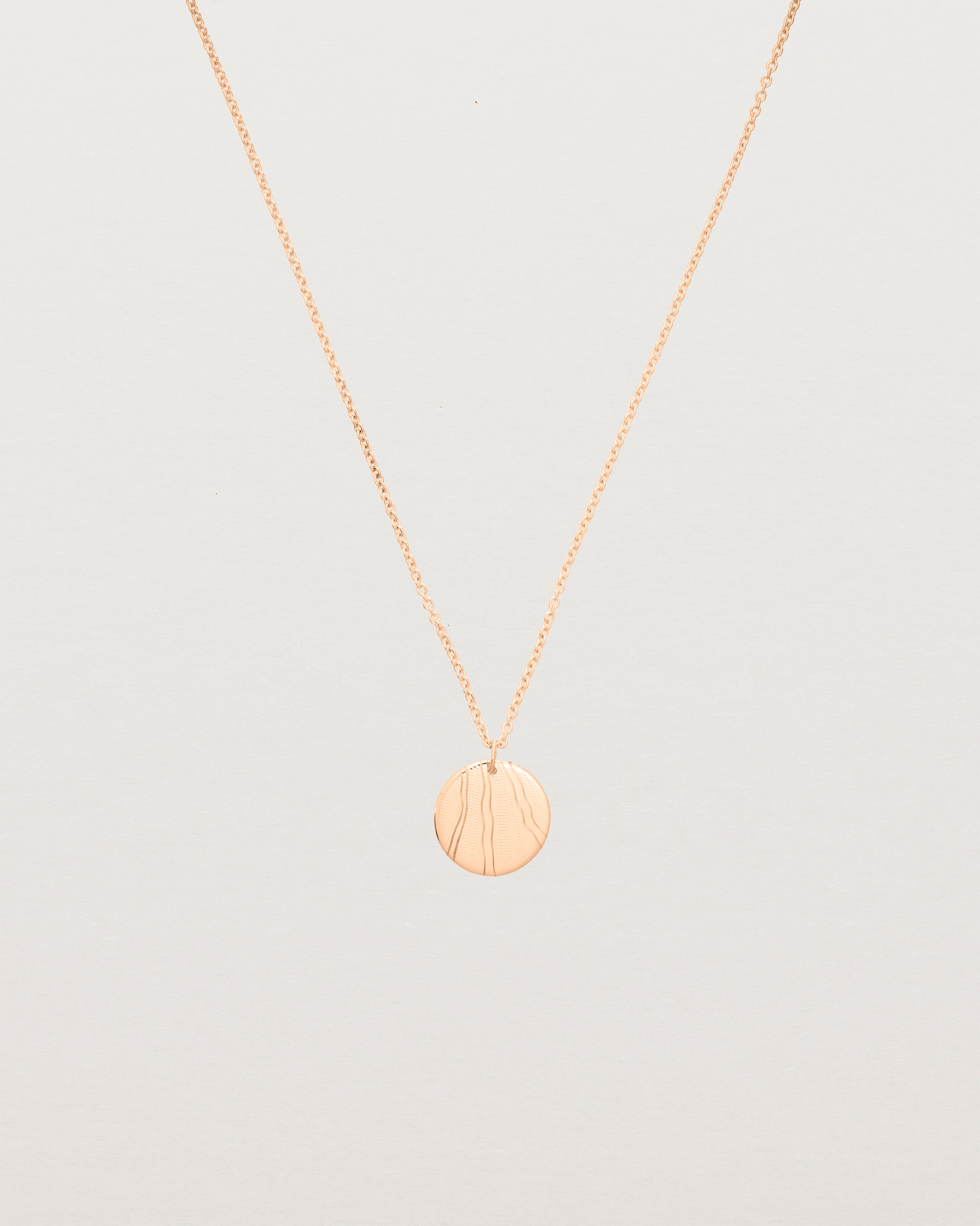 An engraved rose gold pendant