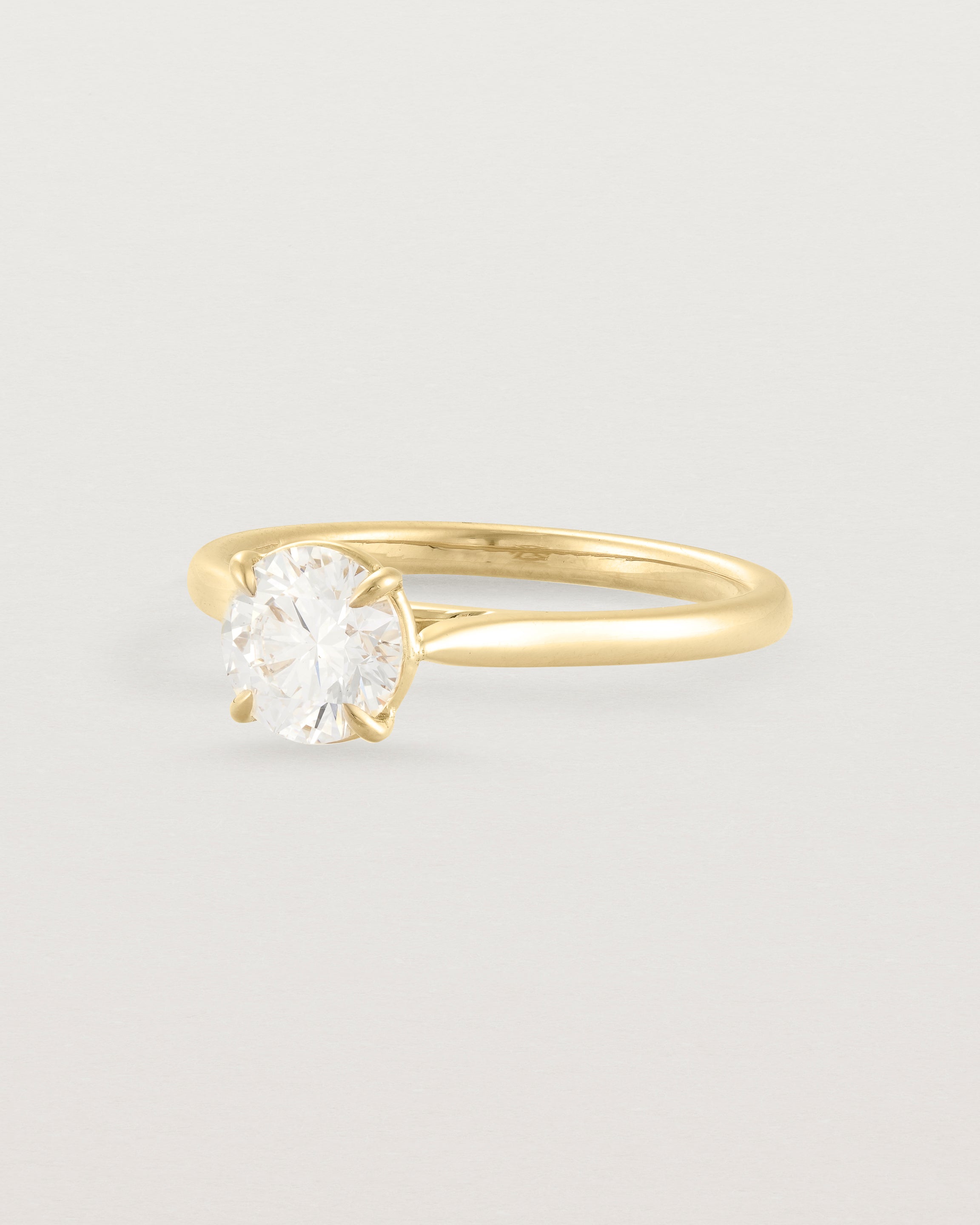 Side view of a 0.90ct round white diamond, adorns a 1.6mm half round 18ct Yellow Gold band.