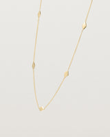 Angled view of the Nuna Charm Necklace in yellow gold.