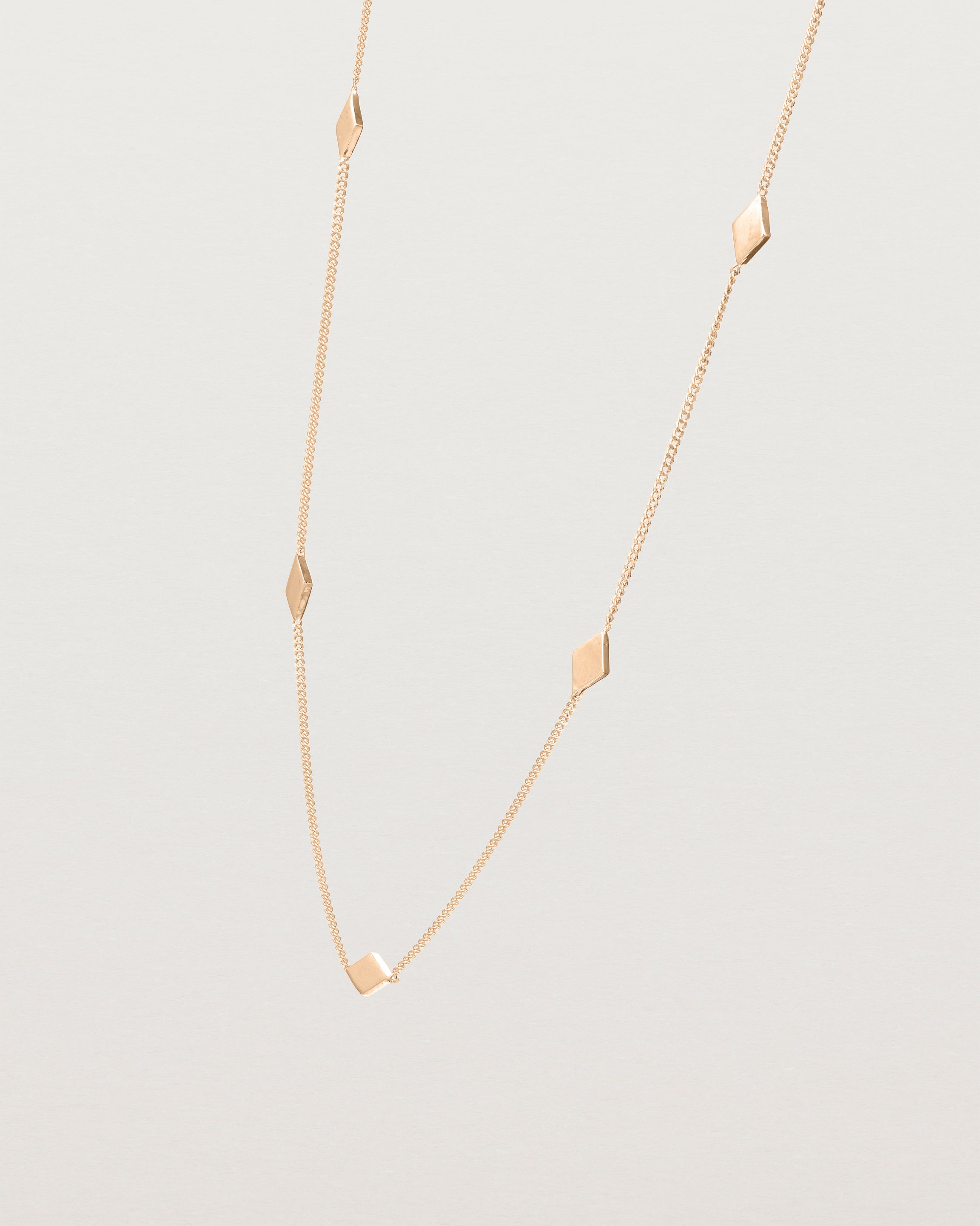 Angled view of the Nuna Charm Necklace in rose gold.