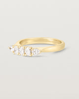 Side on image of diamond engagement ring in yellow gold. Featuring five white diamonds.