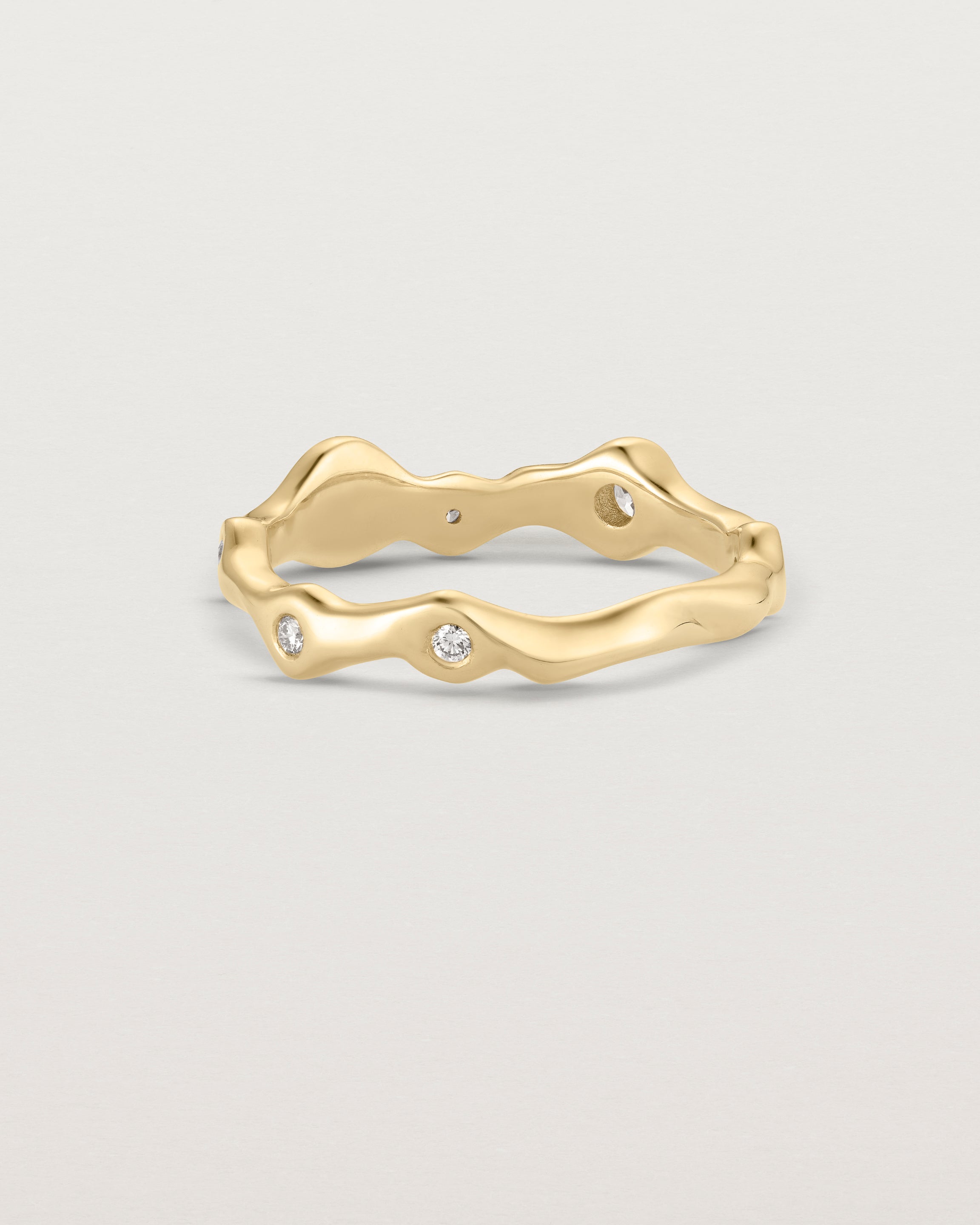 Back facing deep etched image of a yellow gold ring with seven scattered white diamonds.