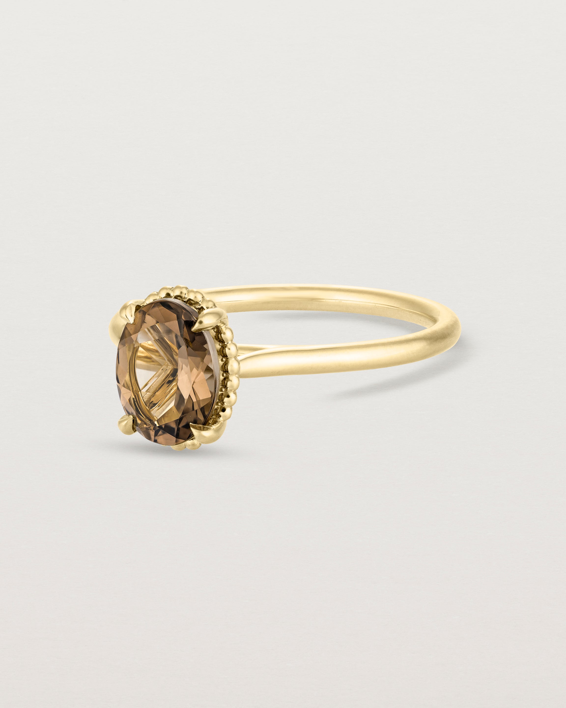 Angled view of the Thea Oval Solitaire | Smokey Quartz in yellow gold.