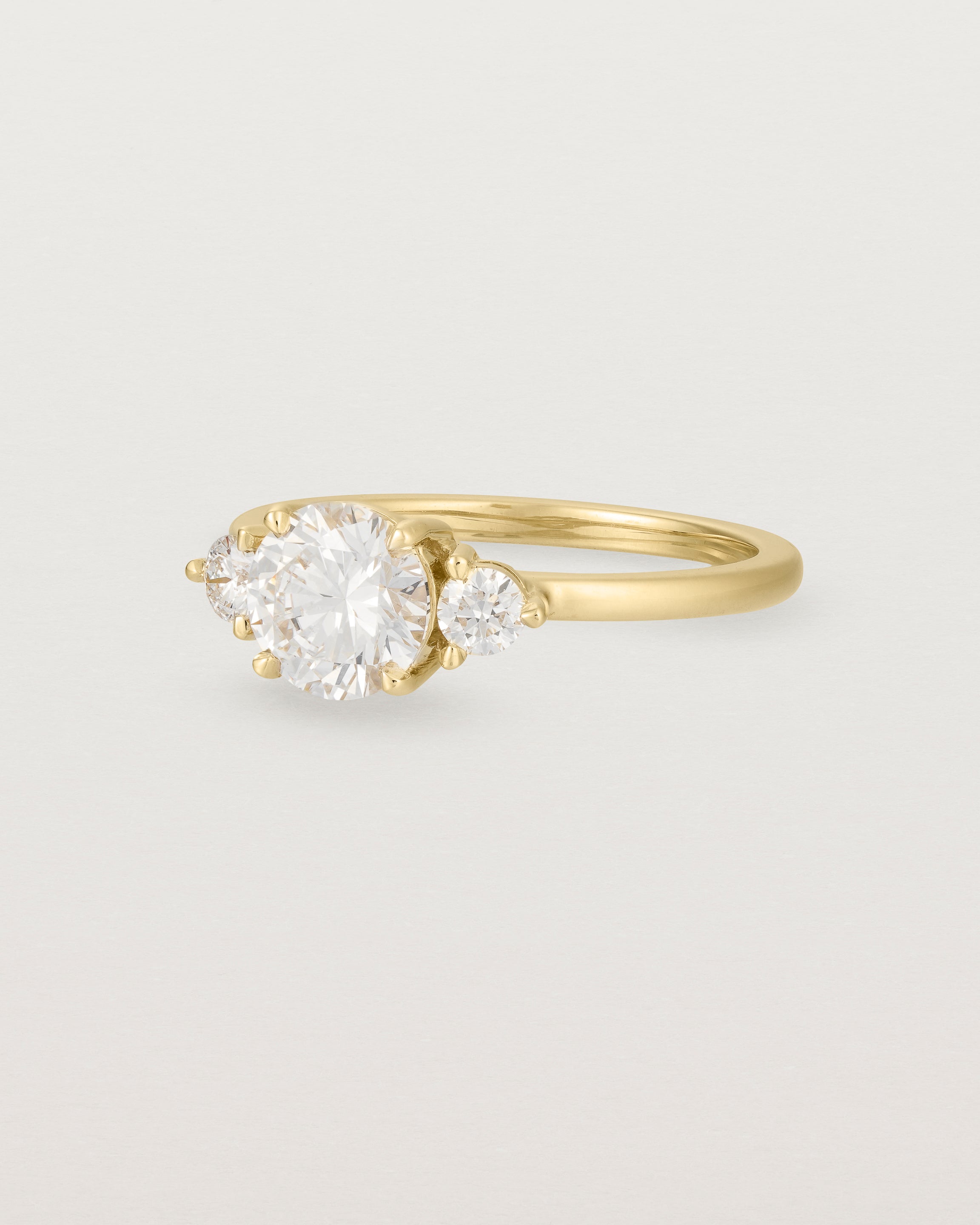 Angled view of the Petite Una Round Trio Ring | Laboratory Grown Diamonds | Yellow Gold.