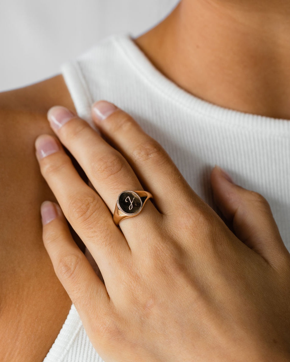 A woman wearing the Initial Signet ring in Rose Gold.