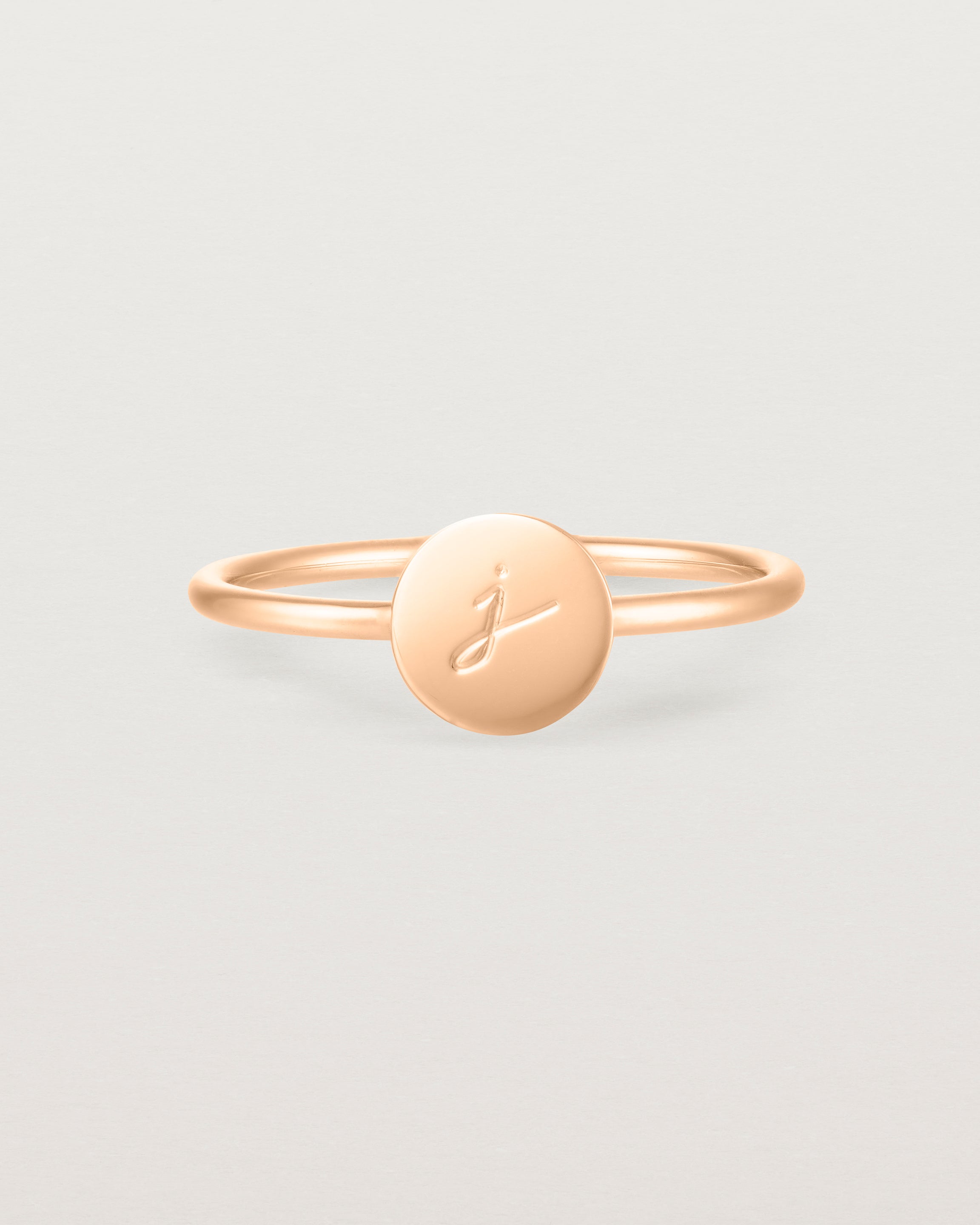 Front view of a rose gold ring featuring a disc with the letter j engraved