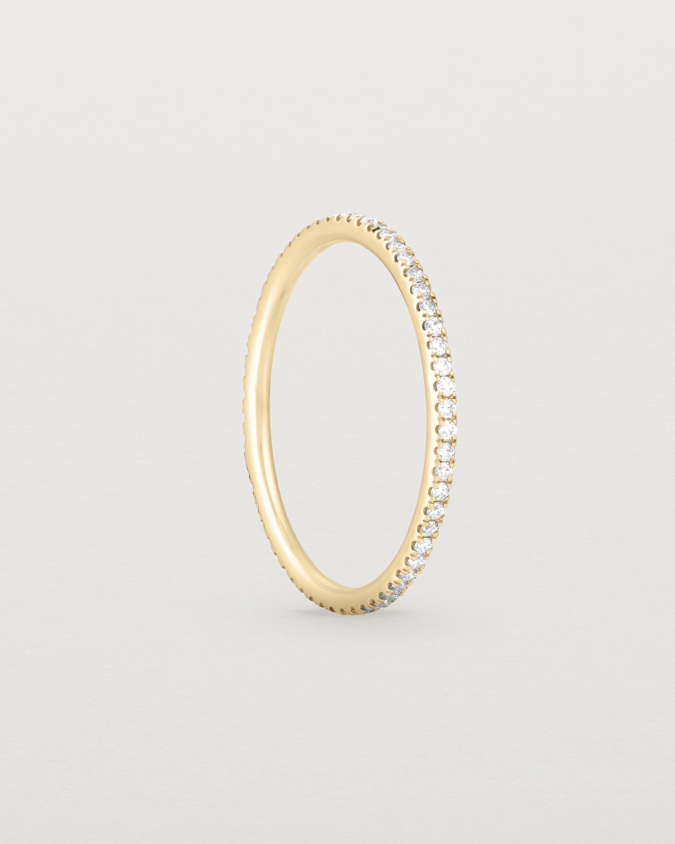 Standing view of a full yellow gold band featuring white diamonds