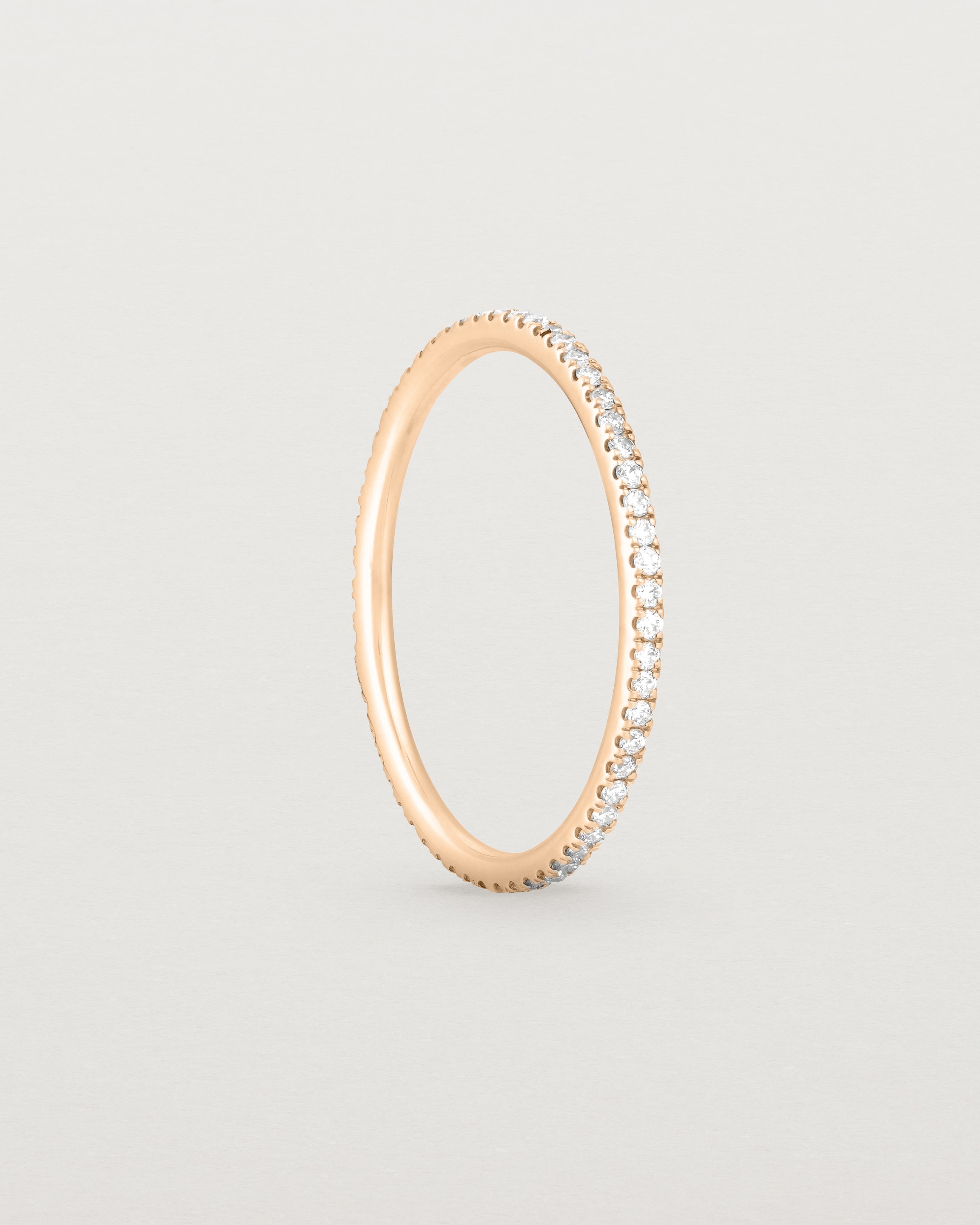 Standing view of a full rose gold band featuring white diamonds