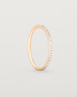 Standing view of a full rose gold band featuring white diamonds
