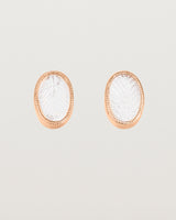 A pair of large oval rose gold studs featuring carved quartz