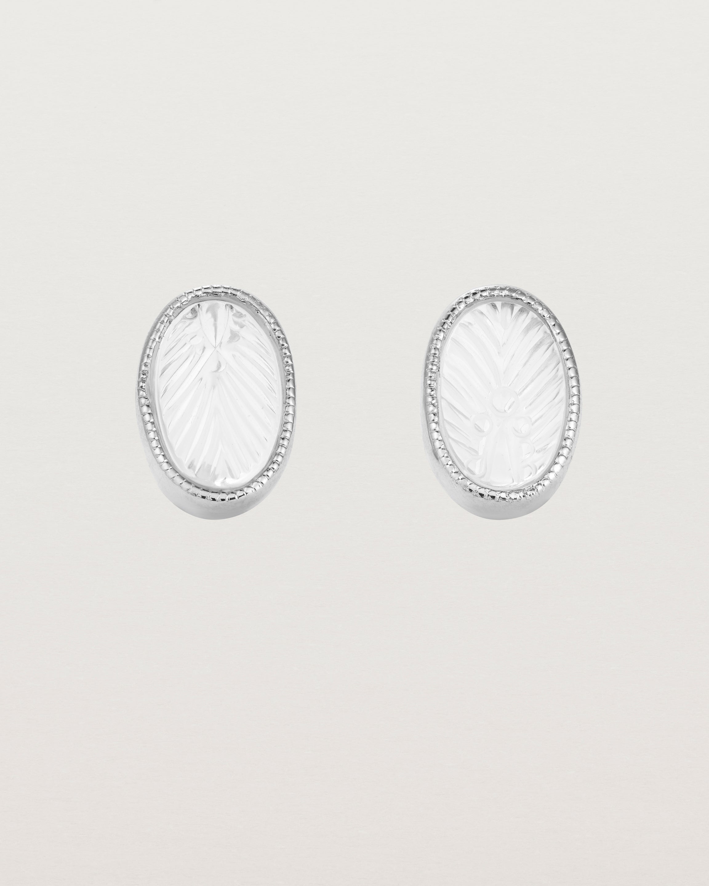 A pair of large oval sterling silver studs featuring carved quartz