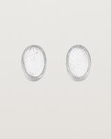 A pair of large oval sterling silver studs featuring carved quartz