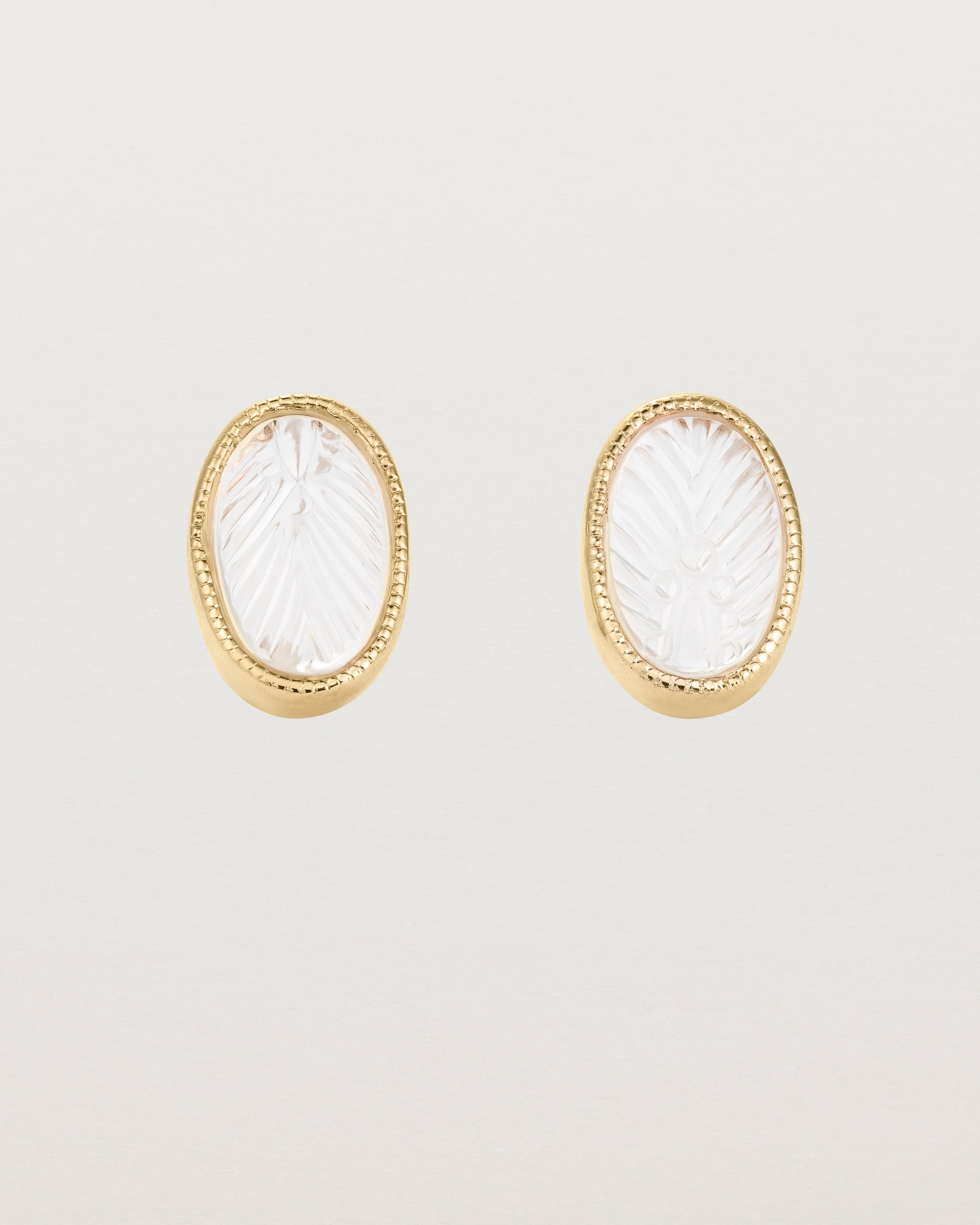 A pair of large oval yellow gold studs featuring carved quartz