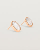 A pair of large oval rose gold studs featuring carved quartz