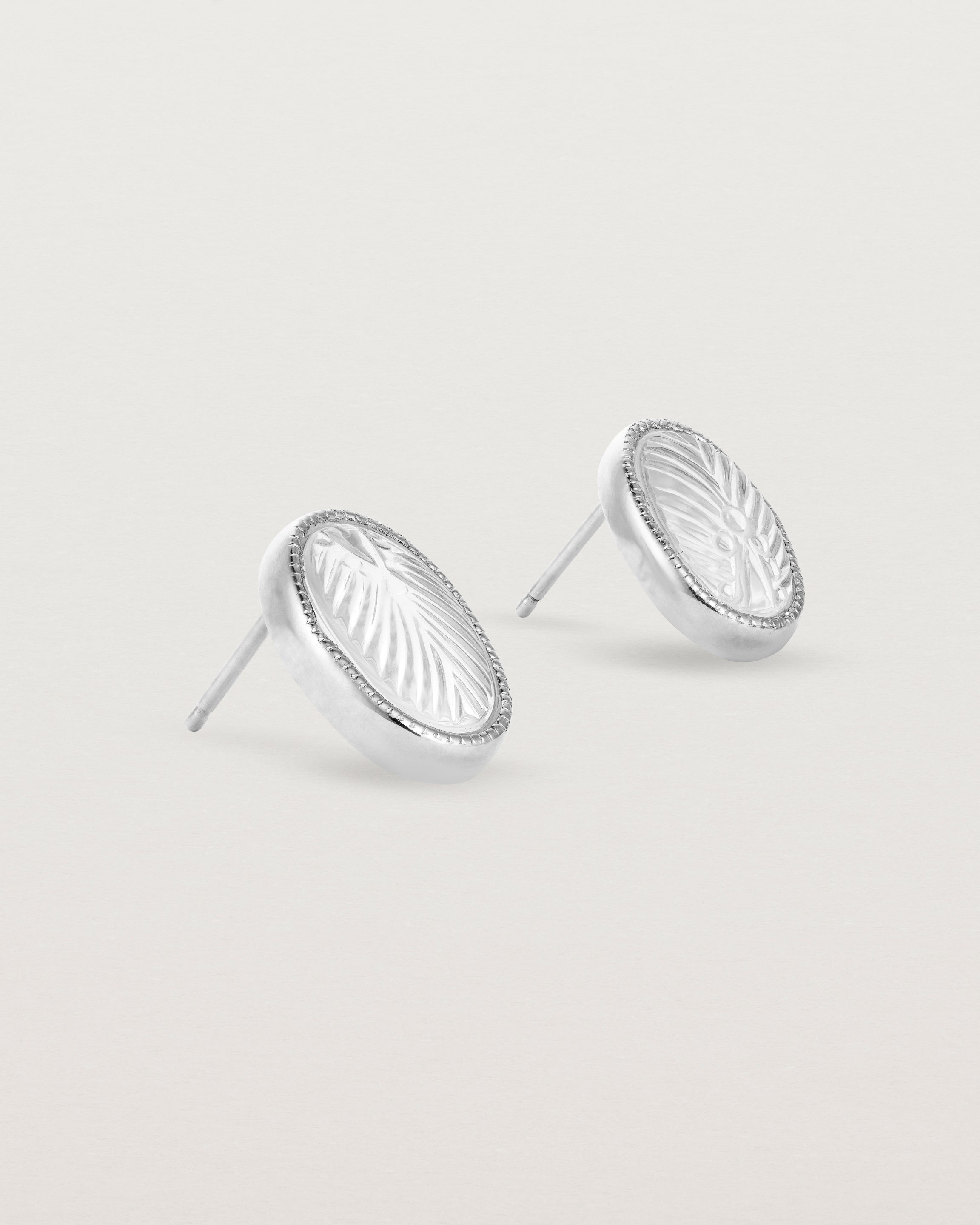 A pair of large oval sterling silver studs featuring carved quartz