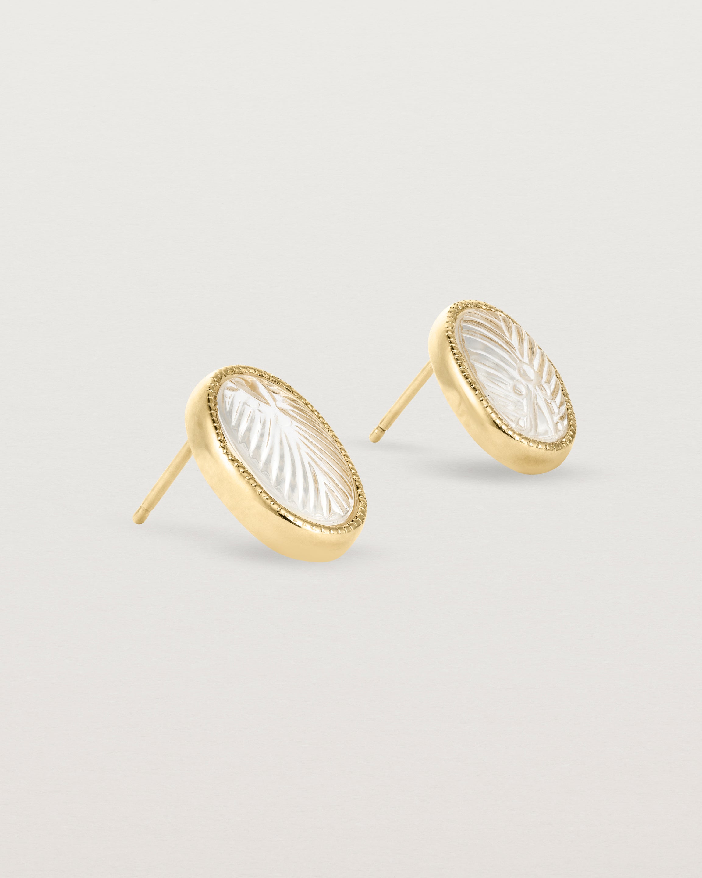 A pair of large oval yellow gold studs featuring carved quartz