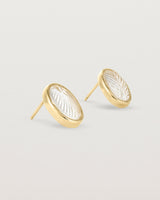 A pair of large oval yellow gold studs featuring carved quartz