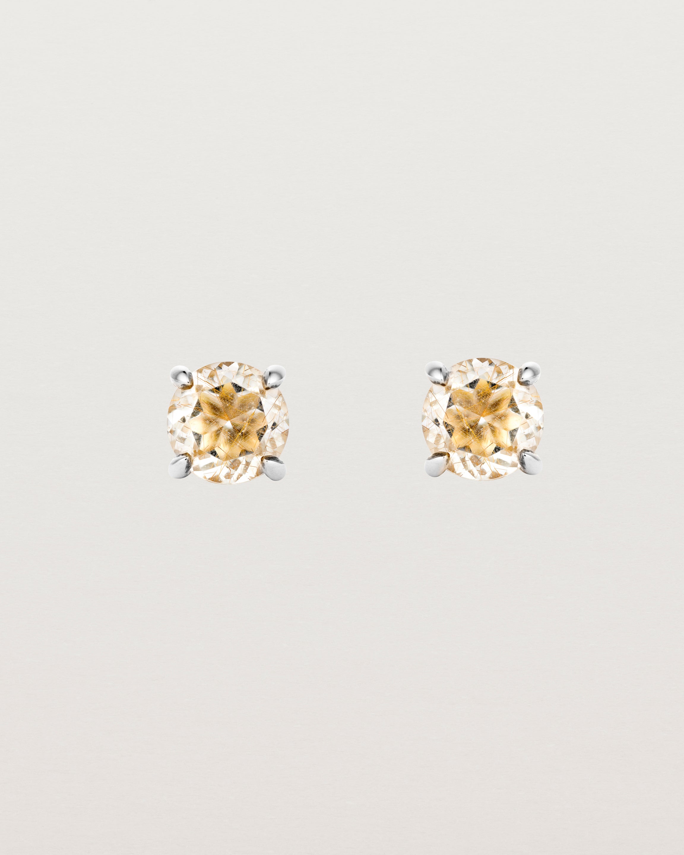 A pair of sterling silver studs featuring a round cut light yellow rutilated quartz stone