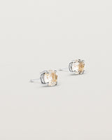 A pair of sterling silver studs featuring a round cut light yellow rutilated quartz stone