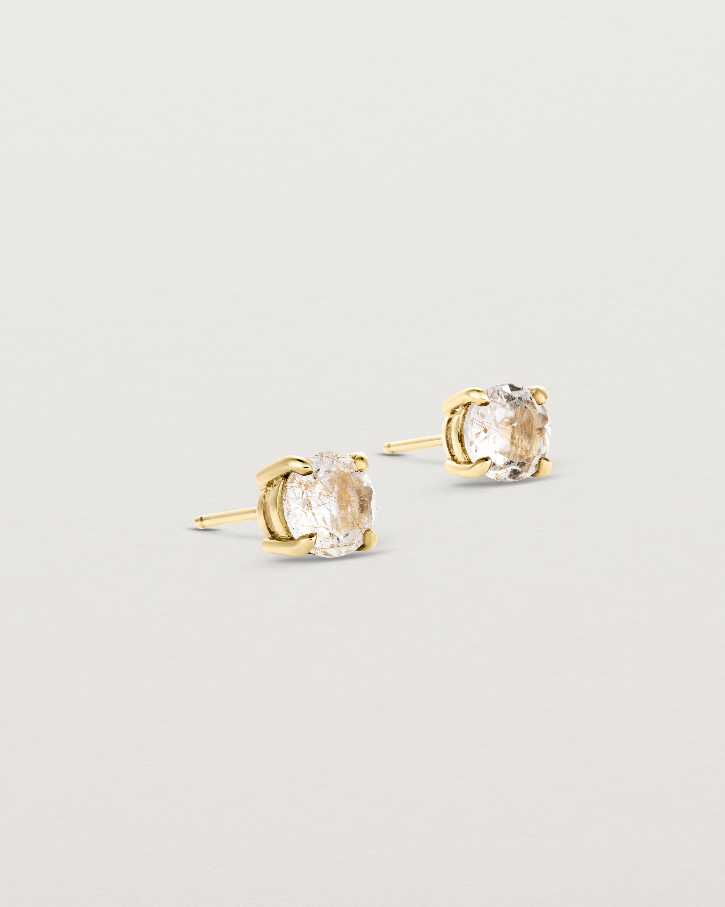 A pair of yellow gold studs featuring a round cut light yellow rutilated quartz stone