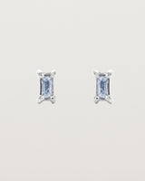 A pair of white gold studs featuring an emerald cut pale blue sapphire