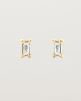 A pair of yellow gold studs featuring an emerald cut white diamond