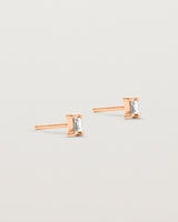A pair of rose gold studs featuring an emerald cut white diamond