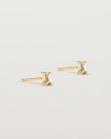 A pair of yellow gold studs featuring an emerald cut white diamond