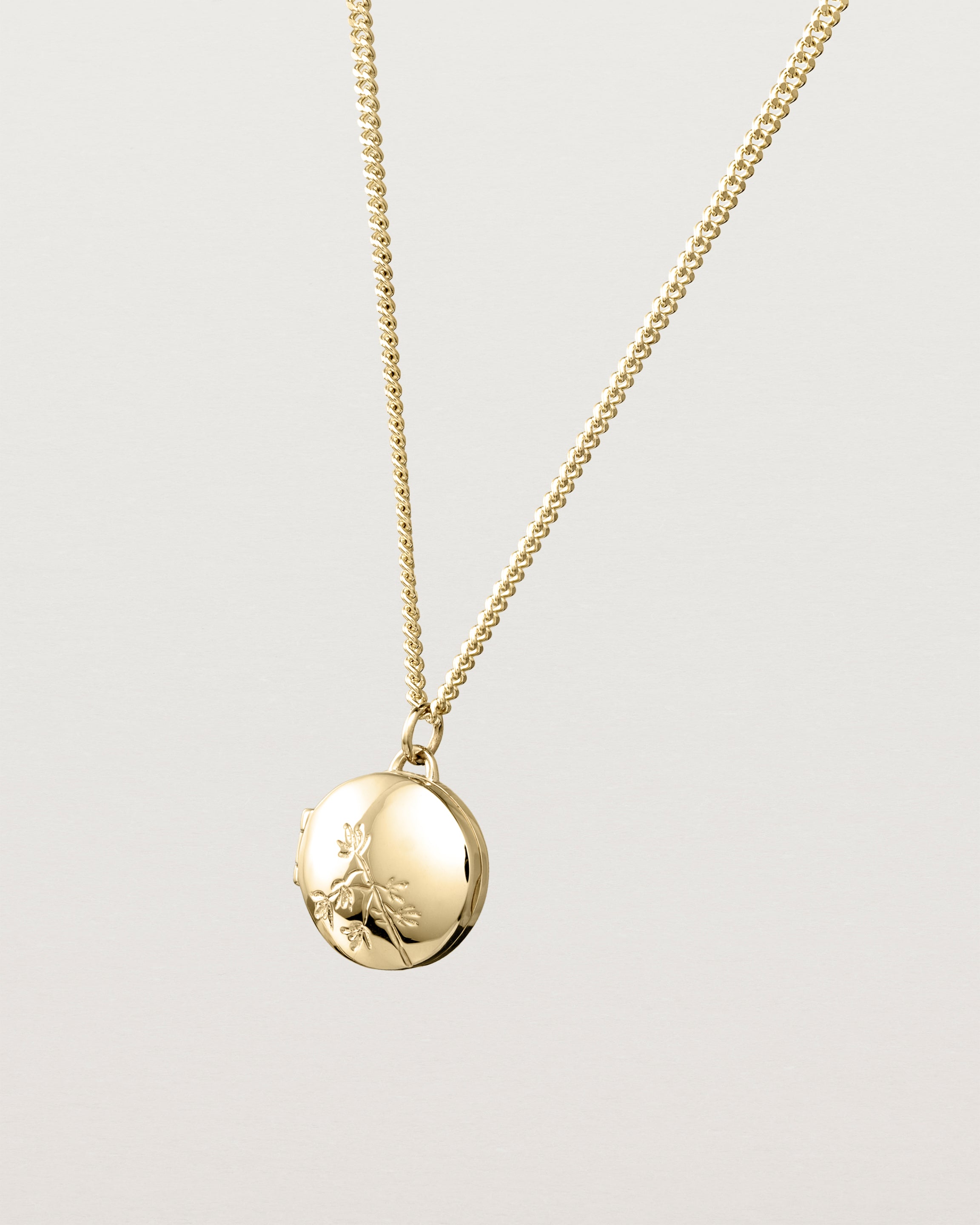 Angled view of the Spotted Orchid Locket in yellow gold.