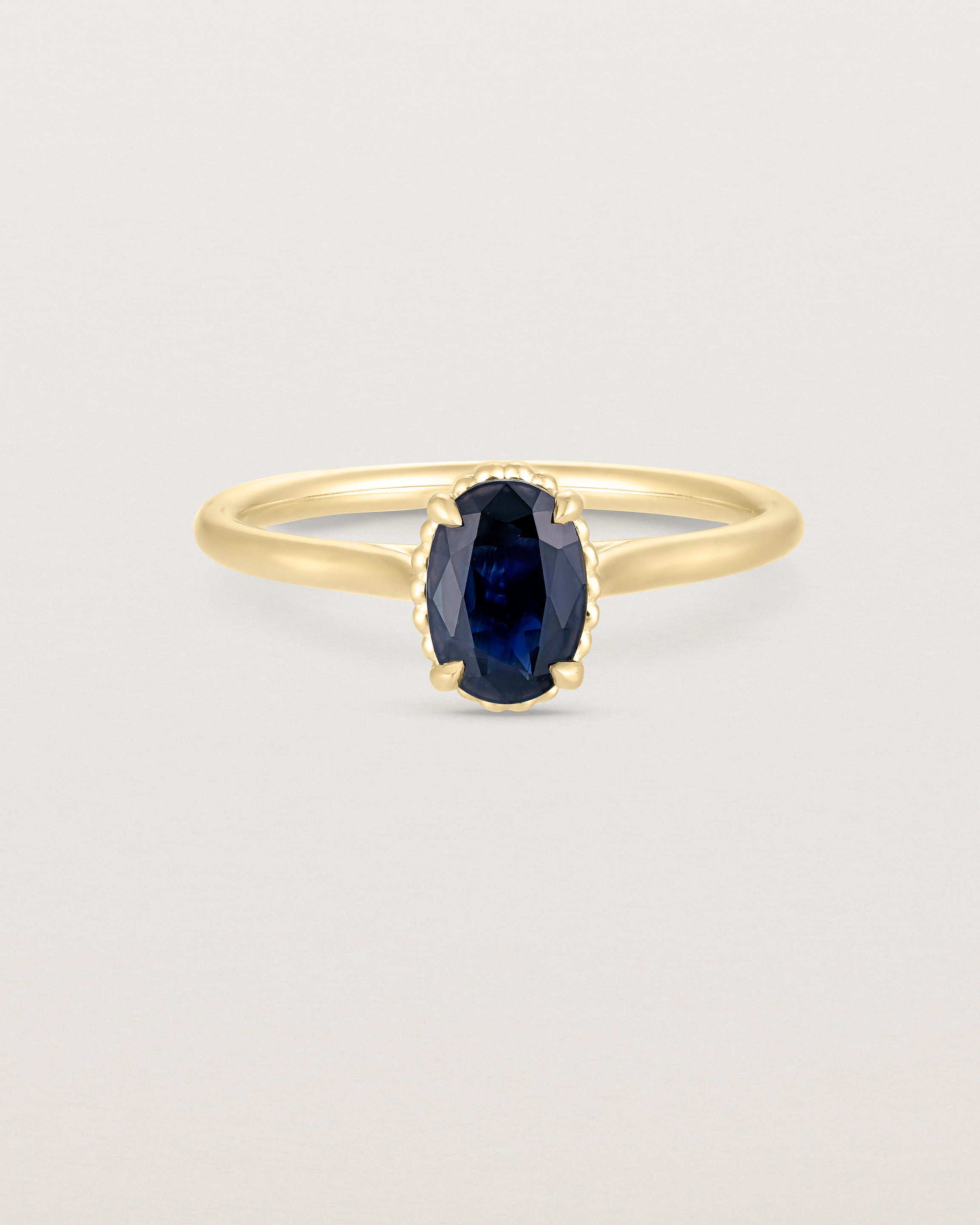 A front view of the Thea Oval Solitaire with a deep blue Australian Sapphire in Yellow Gold