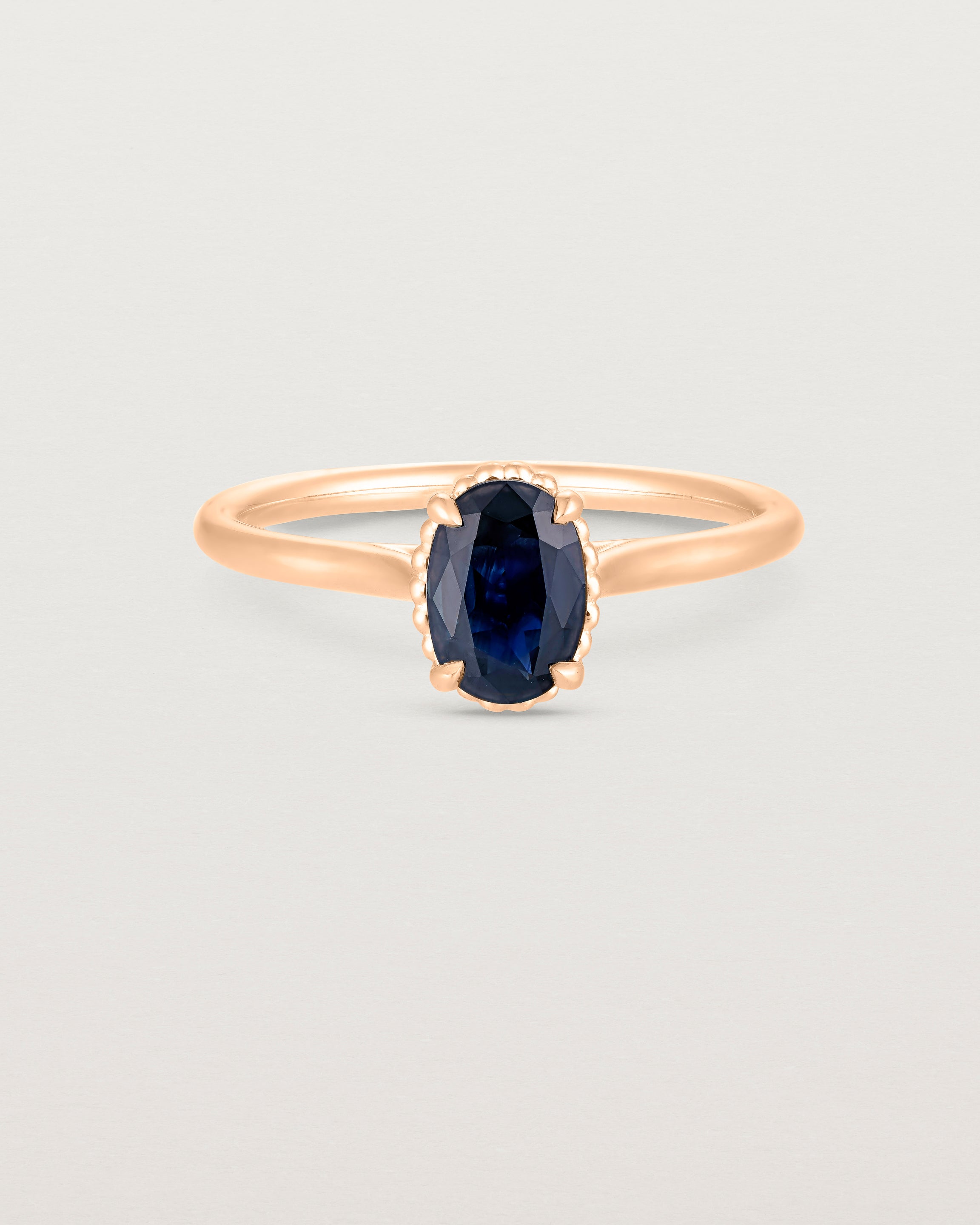 A front view of the Thea Oval Solitaire with a dark blue Australian Sapphire in Rose Gold. 