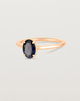 A side view of the Thea Oval Solitaire with a dark blue Australian Sapphire in Rose Gold. 