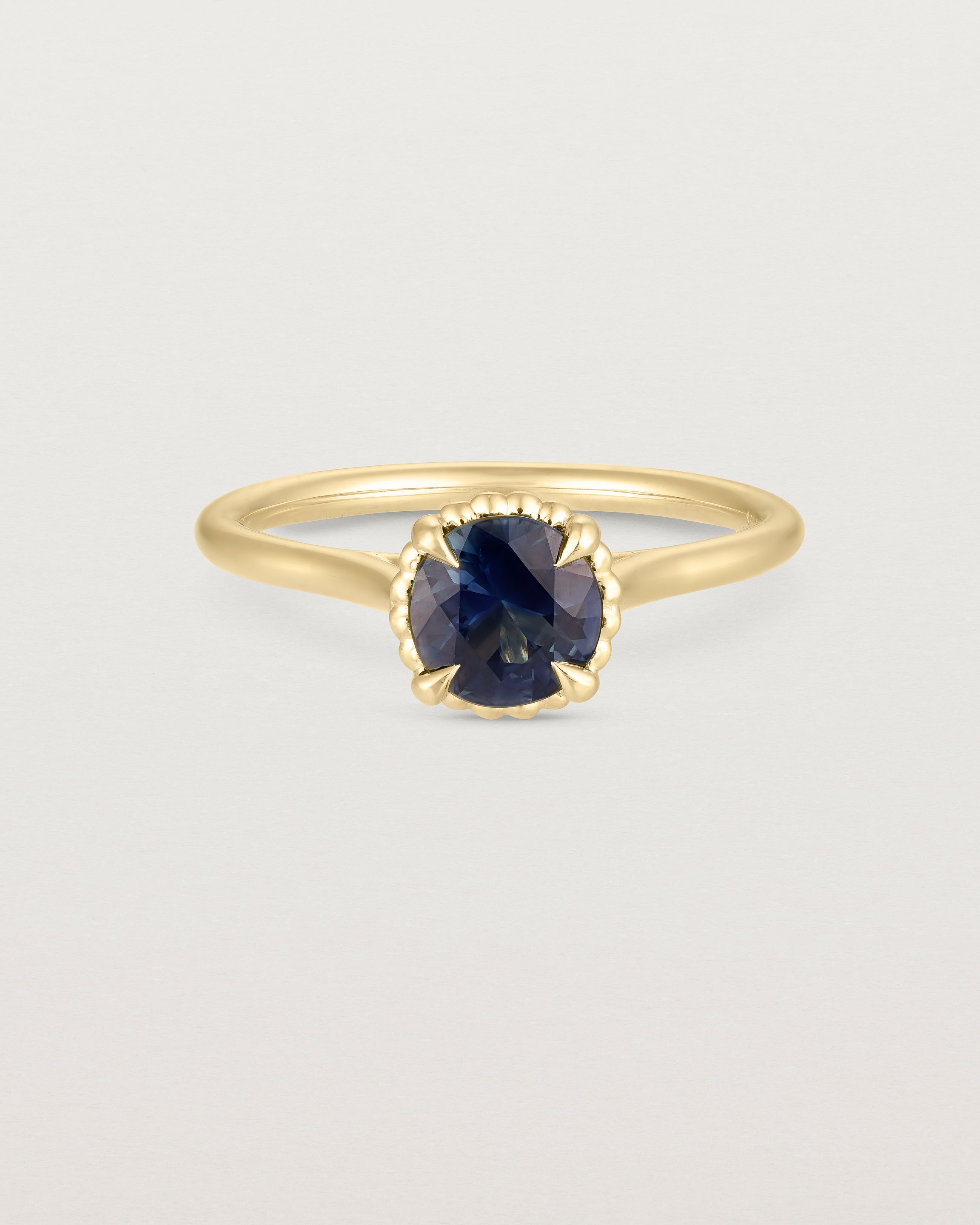 A front view of the the Thea Round Solitaire with a deep blue Australian Sapphire in Yellow Gold
