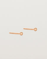 A pair of tiny rose gold studs featuring a round ball