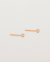 A pair of tiny rose gold studs featuring a round ball