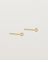 A pair of tiny yellow gold studs featuring a round ball